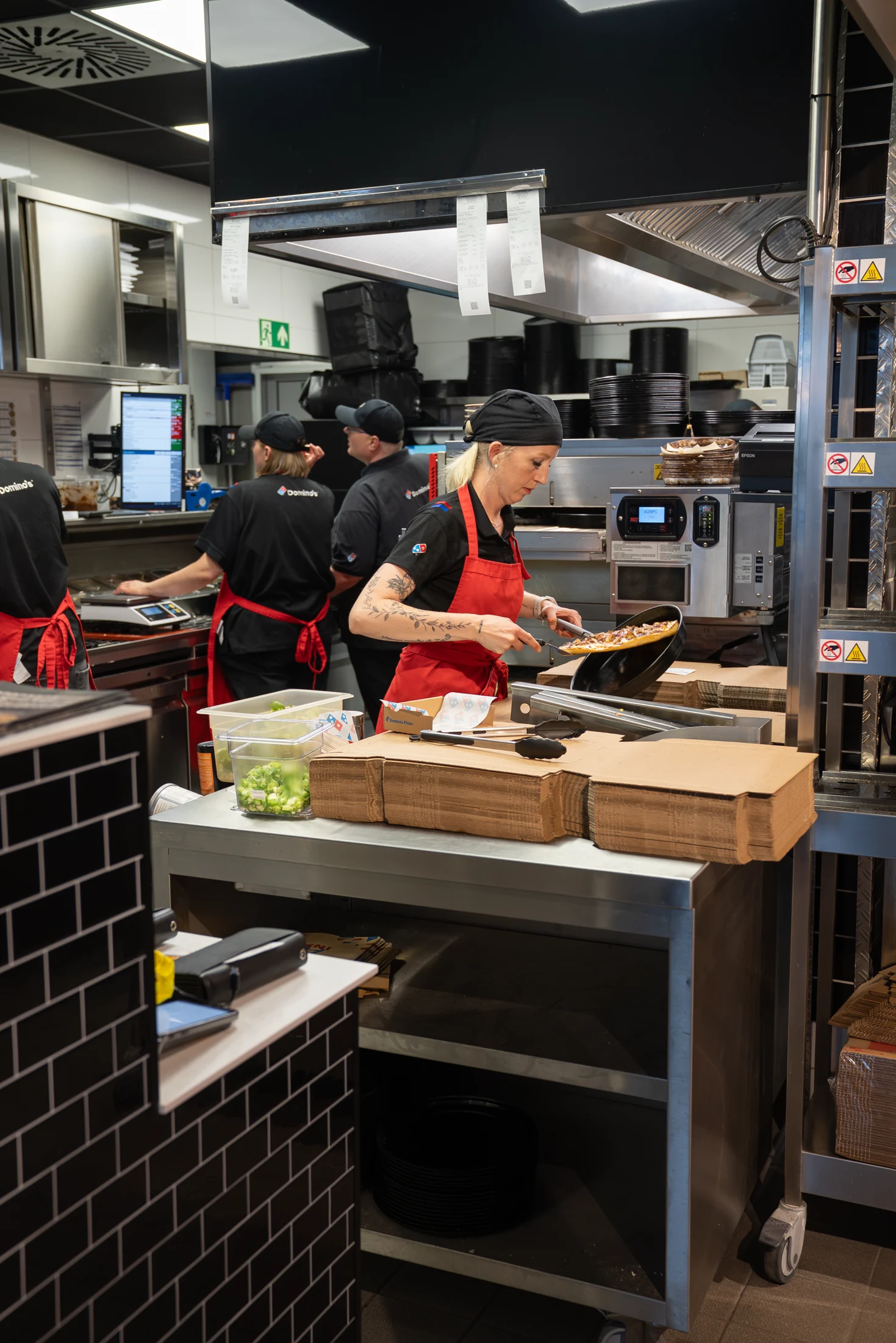 Mitarbeiterin bereitet bei Domino’s Bramsche eine frische Pizza zu