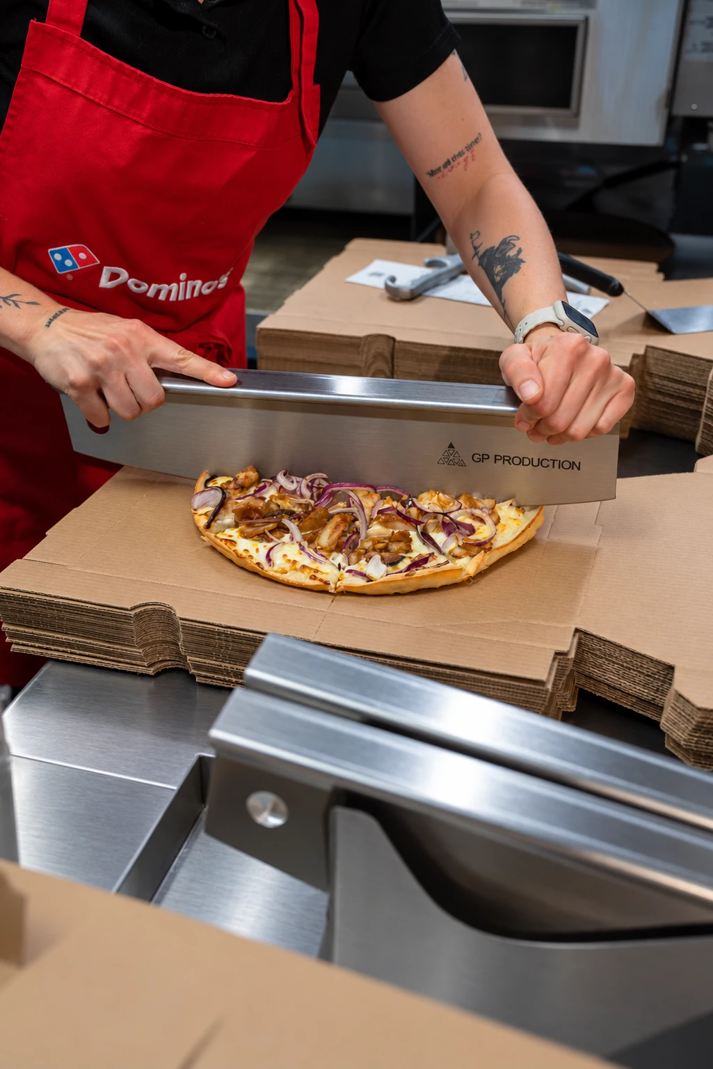 Pizza wird bei Domino’s Bramsche auf sauberer Arbeitsfläche geschnitten